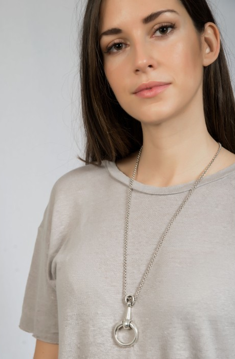 woman wearing silver necklace that features an equestrian pendant in the shape of a bit
