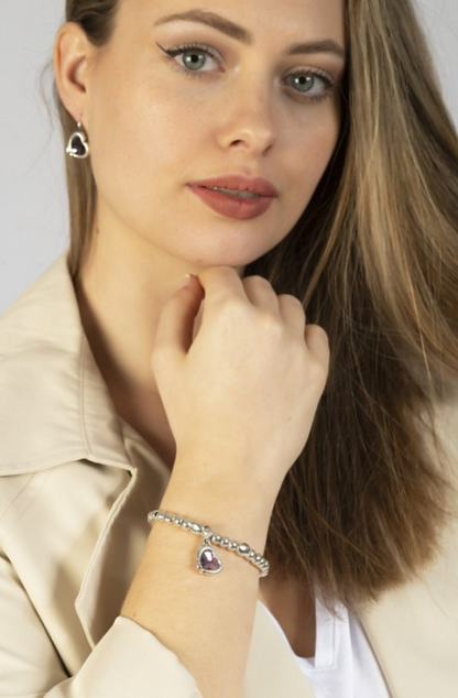 woman wearing silver bracelet with charm pendant and a heart wrapped in cupid's arrow