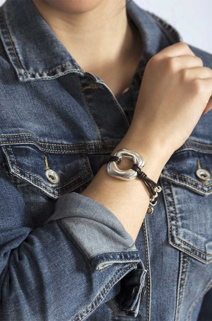 woman wearing bracelet mounted on a leather strap with silver-plated metal pieces