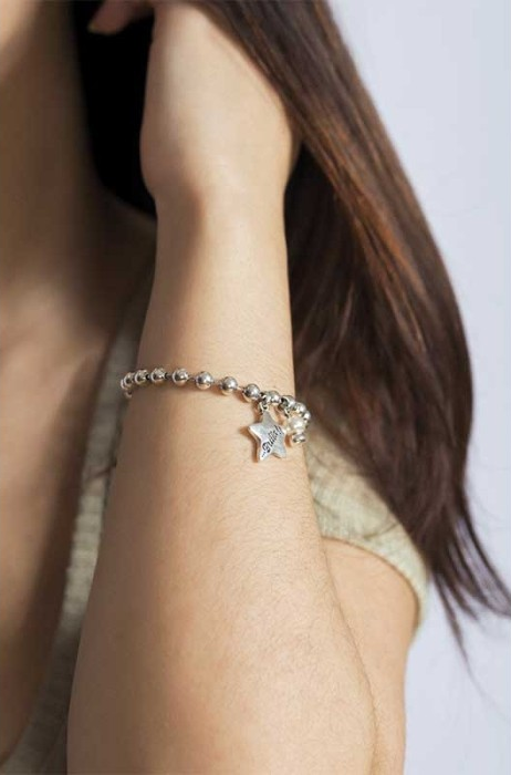 woman wearing elastic silver plated bracelet with bedded design, featuring a ball chain with 10mm hanging star.