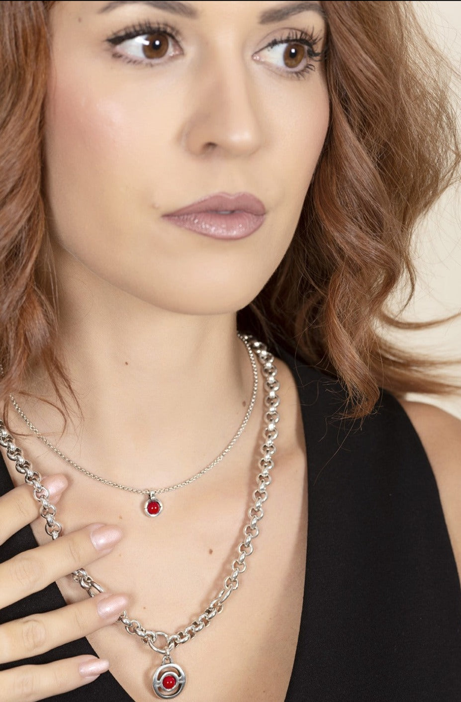 woman wearing silver necklace with mini pendant decorated with a red Murano glass sphere in the center mounted on a chain of link