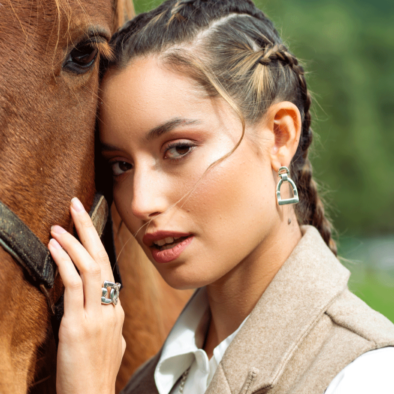 Woman wearing silver earrings inspired by a stirrups design