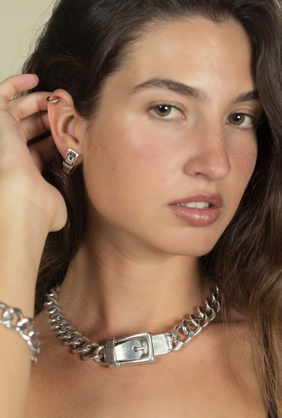 woman wearing silver earrings shaped like buckles