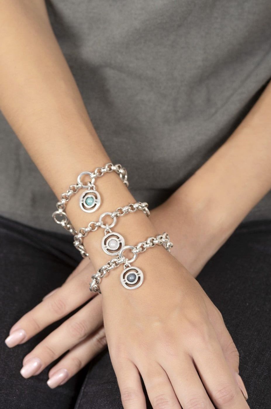 woman wearing silver link bracelet featuring a rolo chain adorned with a green Murano glass charm