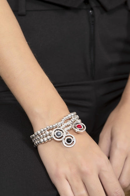 woman wearing silver bracelet with hanging charm decorated with red Murano glass sphere